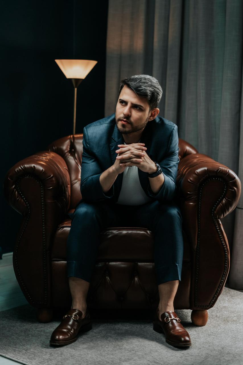 Diego, consultor de investimento imobiliário, sentado em poltrona Chesterfield de couro